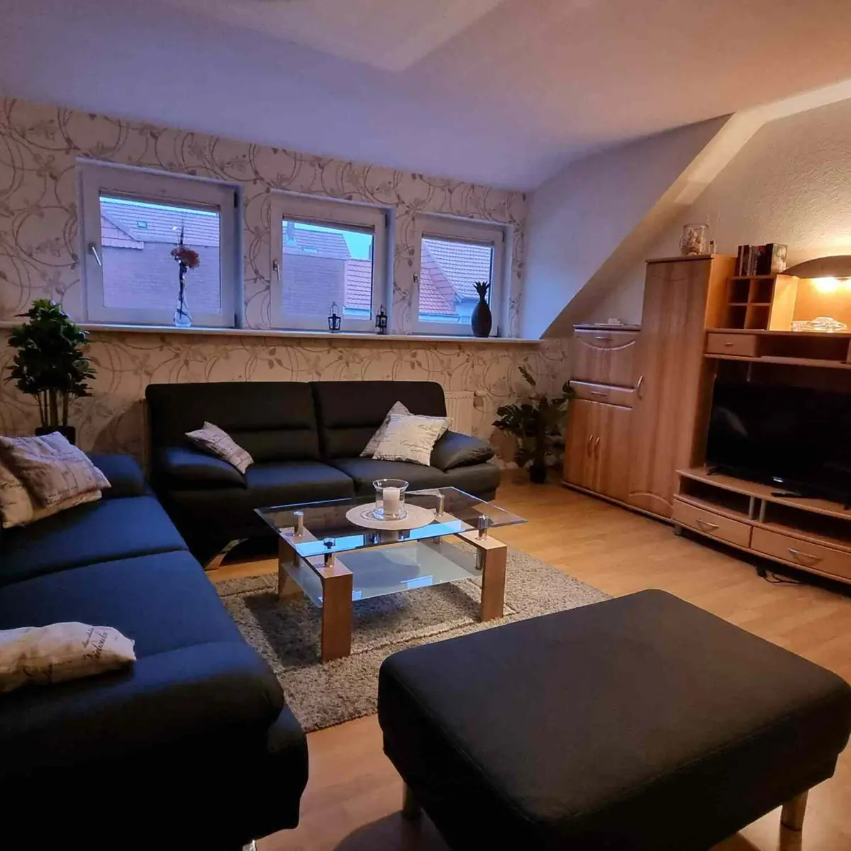Ferienwohnung 1: Wohnzimmer mit Ledercouch und Wohnwand unter der Dachschräge