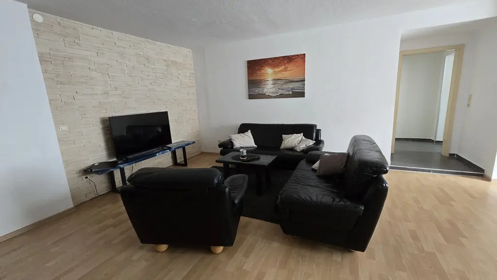 Ferienwohnung 2: helles Wohnzimmer mit Ledersitzgruppe und Fernseher